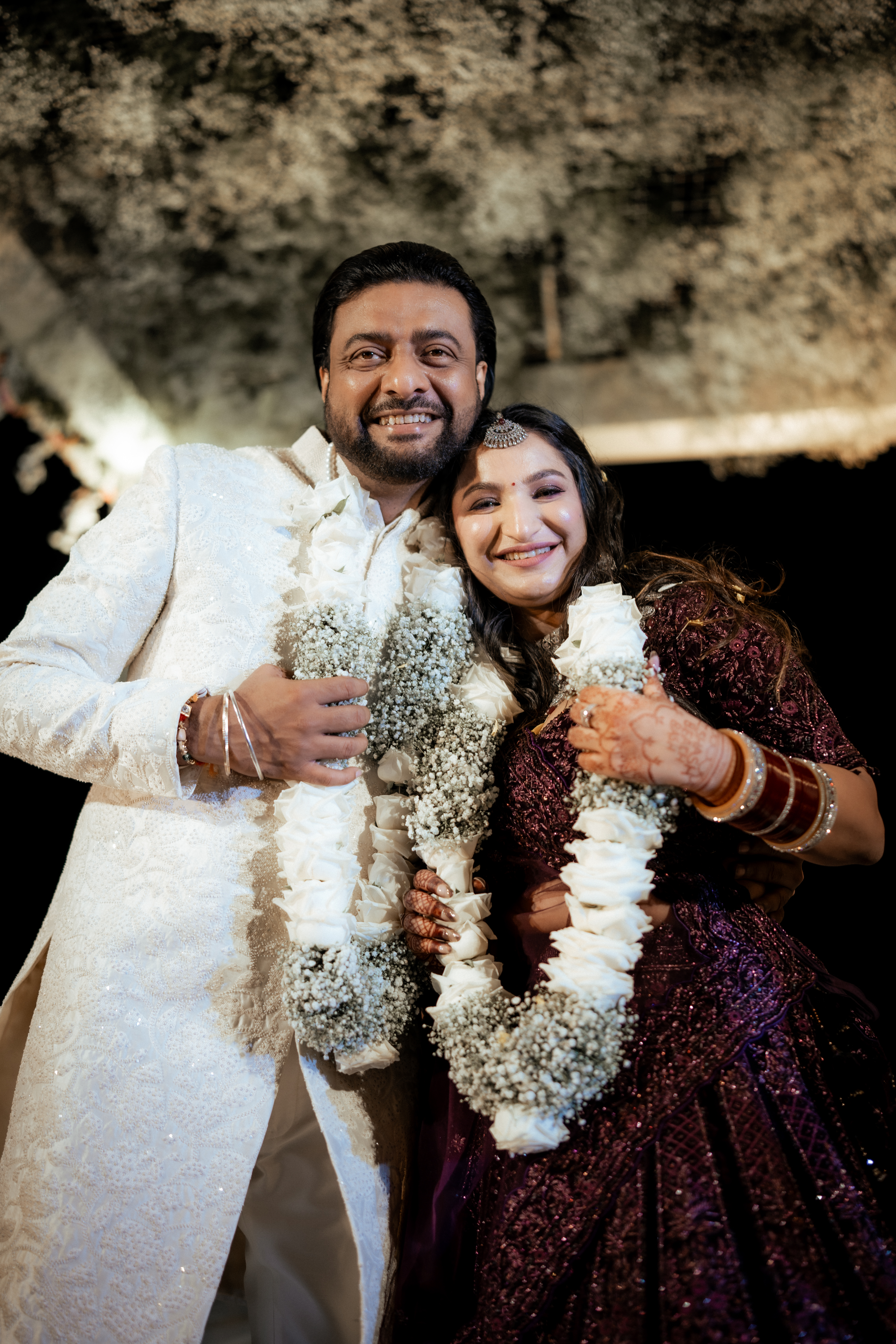 Couple sharing a joyful moment during sangeet celebrations surrounded by friends and family