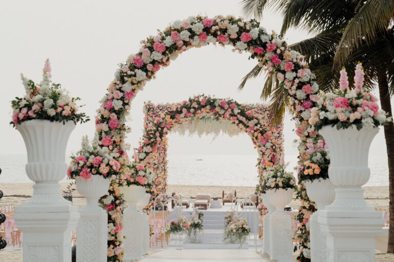 Floral arch setup on the beach for bride’s entrance to the mandap at a destination wedding in Goa