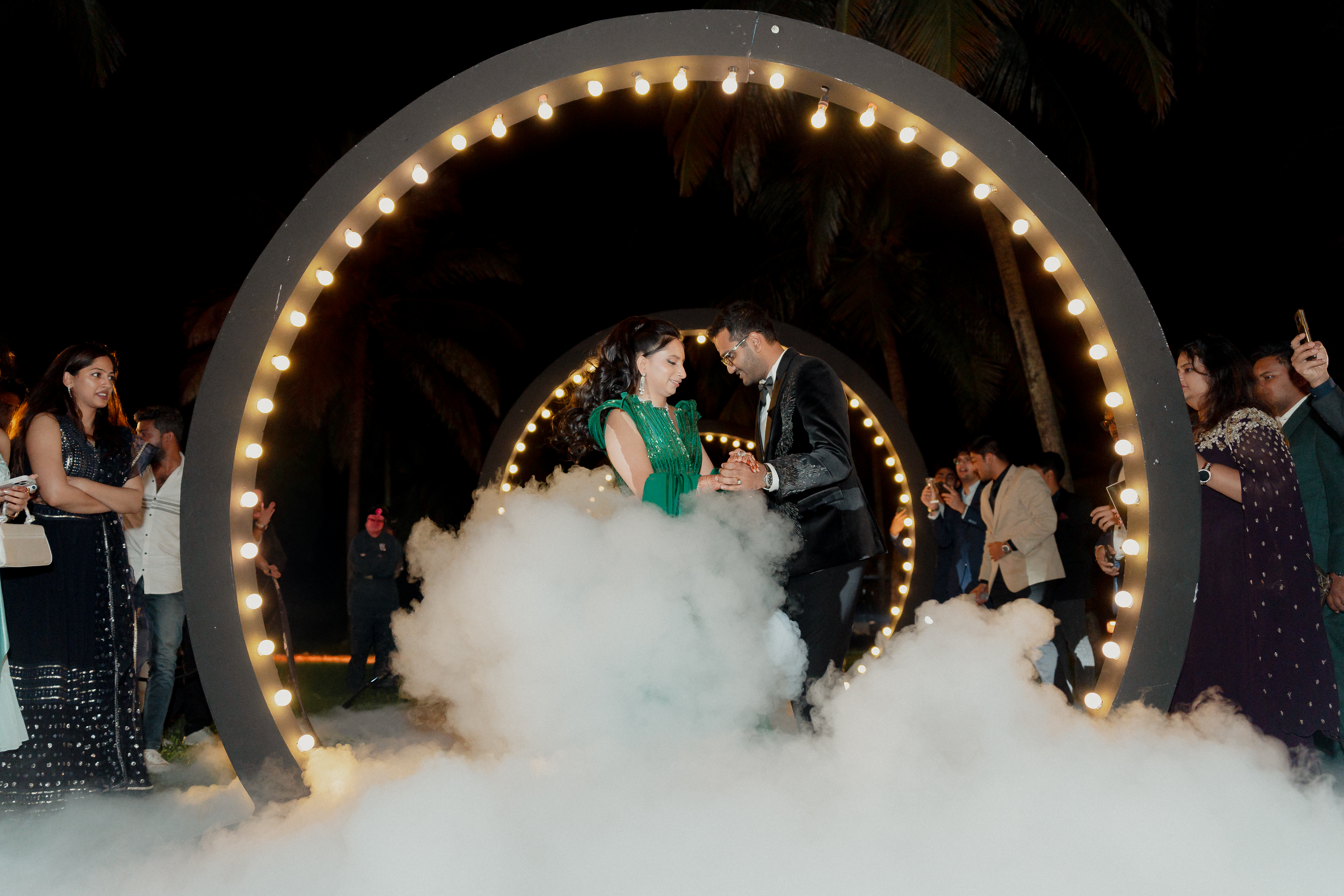 Bride and groom dancing together during their sangeet ceremony with vibrant stage lighting